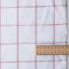 Harmony Checks Linen Blend Fabric. A lightweight linen-cotton blend fabric with a plaid pattern of thin red stripes forming a grid on a light beige background, indicating a composition of 52% linen and 48% cotton and a weight of 135 GSM.