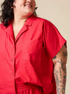 Person wearing a red shirt with a beige background