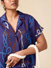 Person wearing a blue patterned shirt with ropes, holding a white rope.