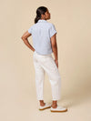 Woman wearing a striped shirt and white pants on a beige background