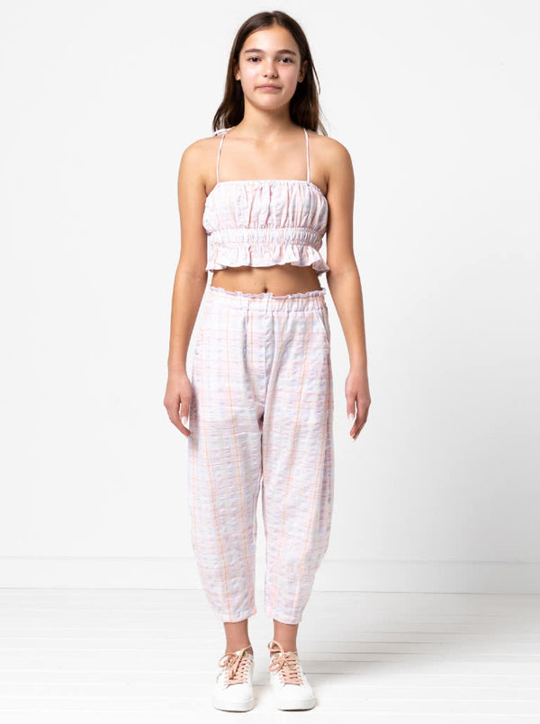 Kids’ shirred crop top with rouleau straps and balloon pants with ruffle and pockets sewing pattern, ideal for light woven fabrics.
