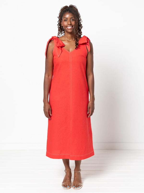 Woman wearing a red dress made using a style arc Esther woven dress sewing pattern with bow details on a white background