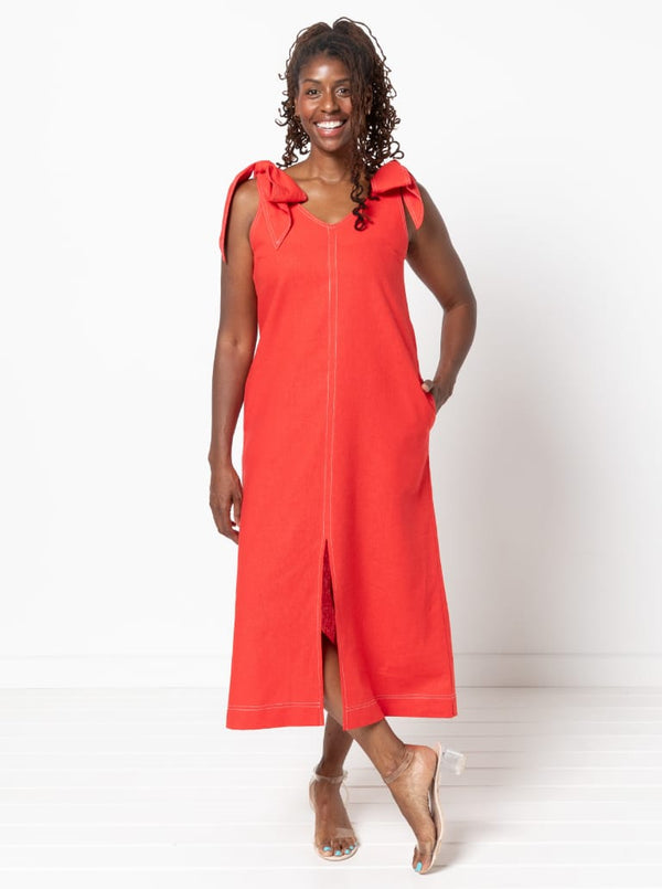 Woman wearing a red dress made using a style arc Esther woven dress sewing pattern with bow straps on a white background