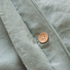 Close-up of a light green fabric with a brown button