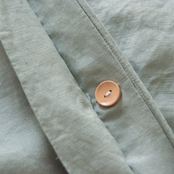 Close-up of a light green fabric with a brown button