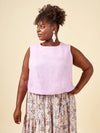 Woman wearing a light purple sleeveless top and floral skirt made using Azure Dress, Skirt, and Top sewing pattern on a beige background