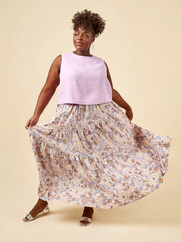 Woman wearing a light purple sleeveless top and floral skirt on a beige background