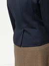 Close-up of a navy blazer made using the Bronnie Tuxedo Jacket Sewing patternand brown skirt on a light gray background