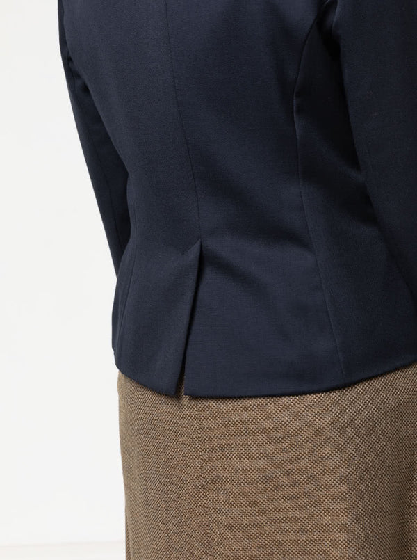 Close-up of a navy blazer made using the Bronnie Tuxedo Jacket Sewing patternand brown skirt on a light gray background