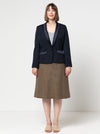 Woman wearing a navy blazer made using the Bronnie Tuxedo Jacket Sewing patternand brown skirt on a white background