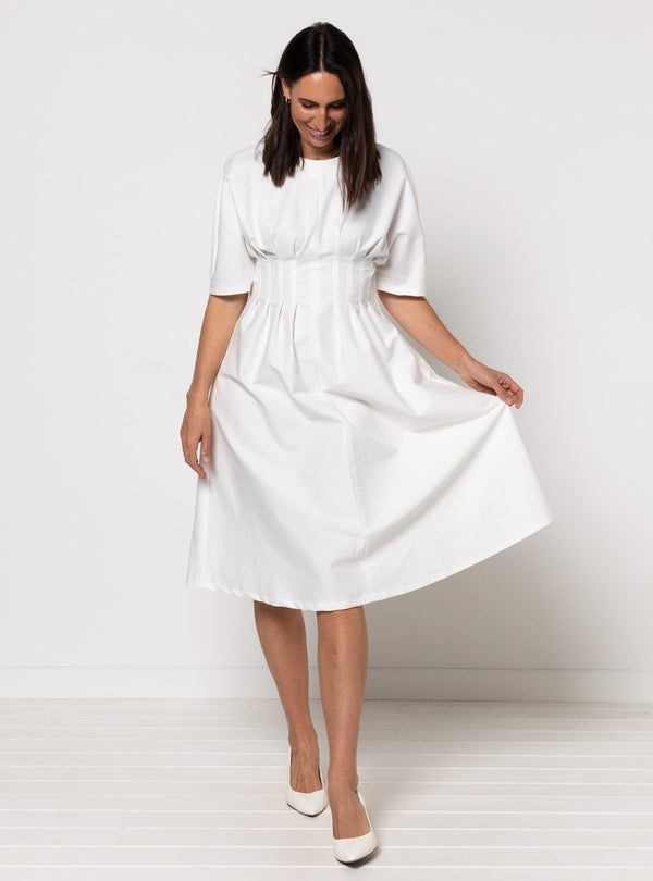 Woman wearing a white dress made using Bronte Woven Dress sewing pattern on a white background