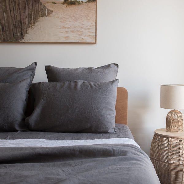 Bedroom with gray bedding and a lamp on a side table.