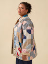 Person wearing a patchwork jacket with a beige background