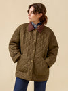 Person wearing a quilted brown jacket against a beige background