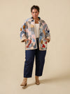Woman wearing a patchwork coat with a beige background
