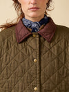 Close-up of a person wearing a quilted jacket with a patterned scarf around their neck.