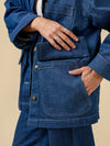 Person wearing a blue denim jacket with a beige background