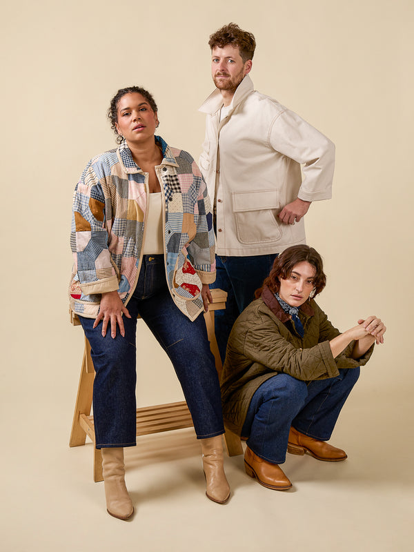 Three people posing together against a beige background