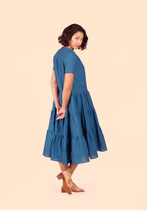 Woman wearing a blue Poppy Dress on a beige background