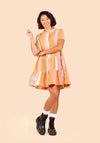 Woman wearing a colorful striped Poppy Dress on a beige background