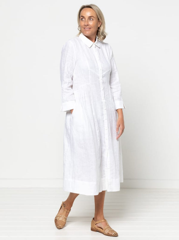 Woman wearing a white dress against a white backgroundThe dress is made from the Hampton Woven Dress Sewing Pattern – a mid-calf shirtdress with a gathered skirt, curved waist, sleeve or sleeveless options, and inseam pockets.