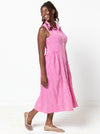 Woman wearing a pink checkered dress on a white background. the dress made using Hampton Woven Dress Sewing Pattern – Mid-calf shirtdress with gathered skirt, curved waist, sleeve or sleeveless options, and inseam pockets.