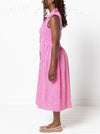 Woman wearing a pink checkered dress against a white backgroundThe dress is made from the Hampton Woven Dress Sewing Pattern – a mid-calf shirtdress with a gathered skirt, curved waist, sleeve or sleeveless options, and inseam pockets.