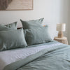 Bed with Harbour Sage flat sheet 100% linen bedding and pillows in a bedroom setting.