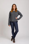 Woman wearing a gray sweater and blue jeans on a white background