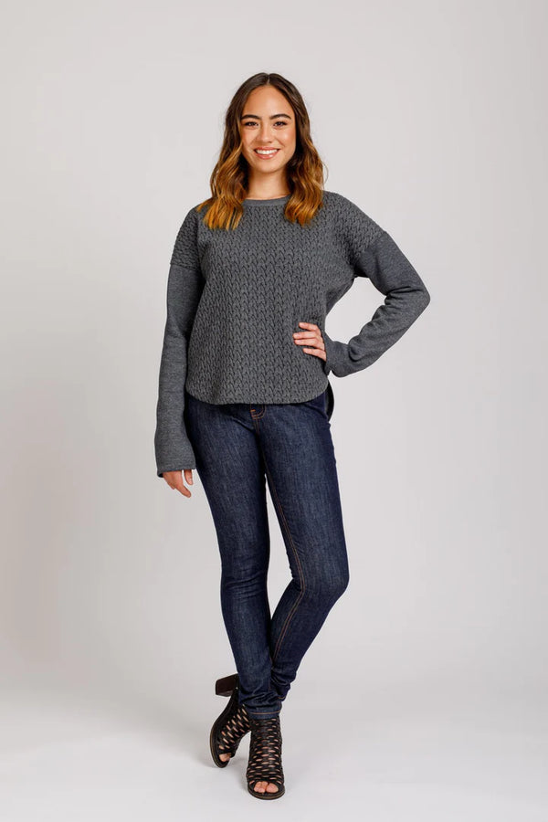 Woman wearing a gray sweater and blue jeans on a white background