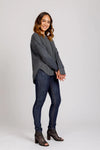 Woman wearing a gray sweater and blue jeans on a white background