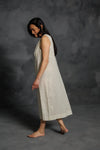 Woman wearing a beige dress made using The Lilian Sewing Pattern by Merchant & Mills against a dark gray background