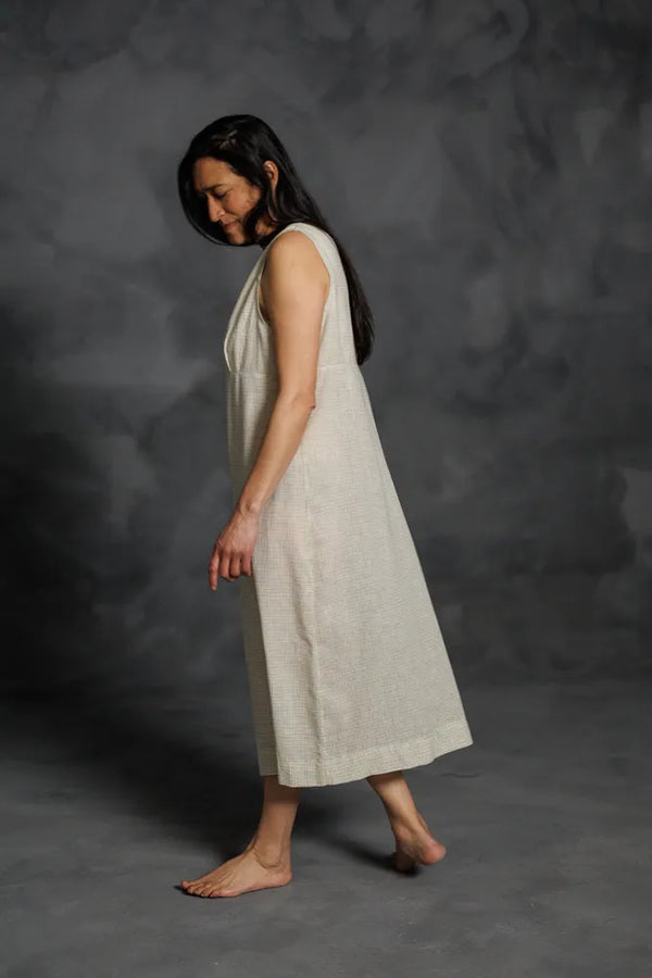 Woman wearing a beige dress made using The Lilian Sewing Pattern by Merchant & Mills against a dark gray background