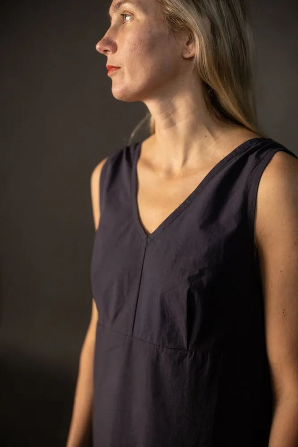 Woman wearing a dark sleeveless dress made using The Lilian Sewing Pattern by Merchant & Mills against a dark background
