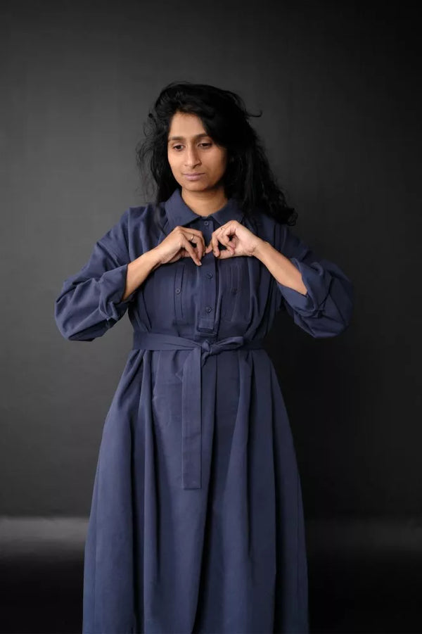 Woman wearing a long blue The Cawley Sewing Pattern by Merchant & Mills against a dark background