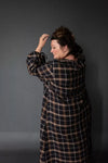 Person wearing a plaid coat against a gray background