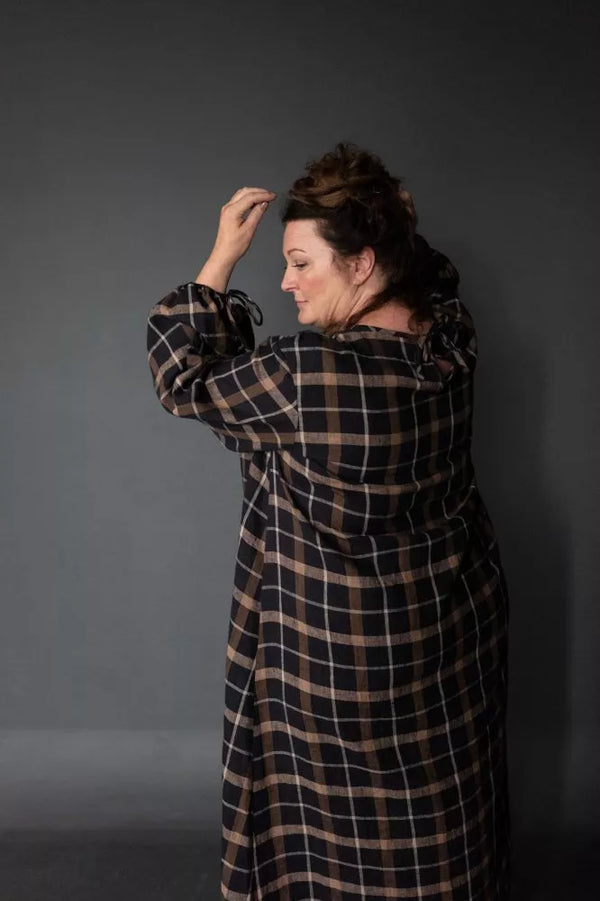 Person wearing a plaid coat against a gray background