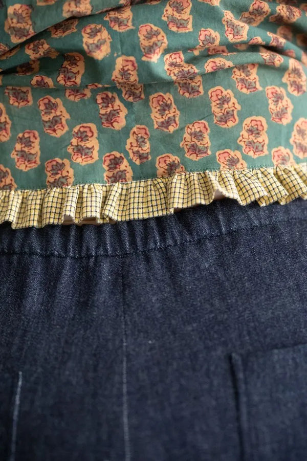 Close-up of a fabric with floral pattern and ruffled edge on a dark background