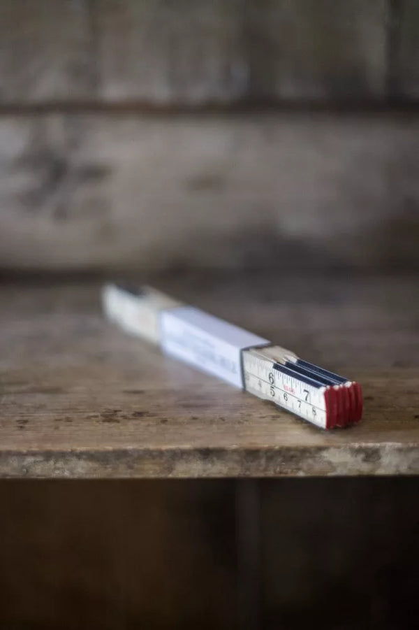 Vintage Merchant & Mills 1-metre wooden folding rulerwith measurements on a wooden surface