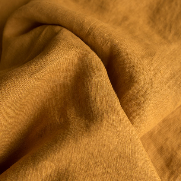 Close-up of Mustard extra wide 100% linen fabric with visible texture