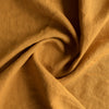 Close-up of Mustard extra wide 100% linen fabric fabric with folds