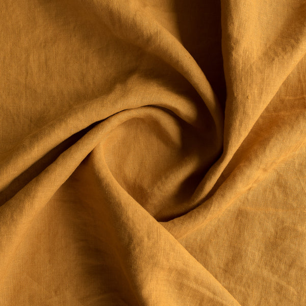 Close-up of Mustard extra wide 100% linen fabric fabric with folds