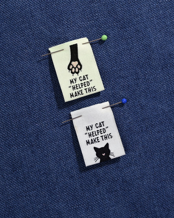 Two small fabric patches with cat illustrations and text on a blue background
