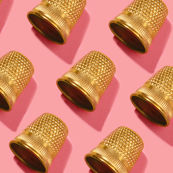 Gold thimble on a pink and purple gradient background