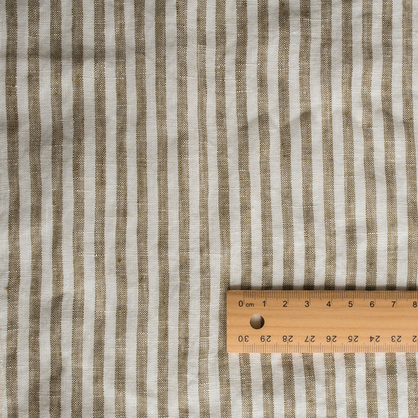 Olive Stripe 100% Linen Fabric with 0.5cm yarn-dyed stripes in olive green and off-white – extra wide, European Flax™ certified with a wooden ruler for scale