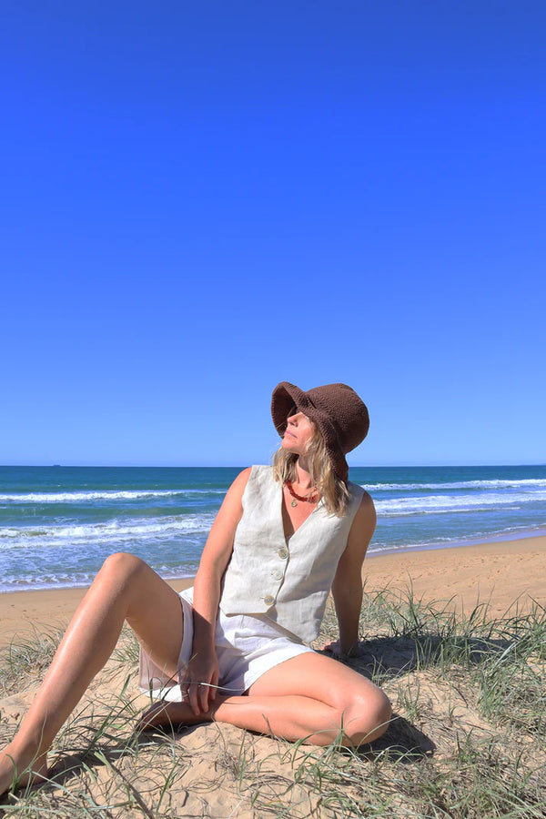 Pipit Vest Sewing Pattern - Reversible Oversized Vest in Two Lengths. Image of A woman wearing pipit vest made of natural colour linen fabric in the beach side