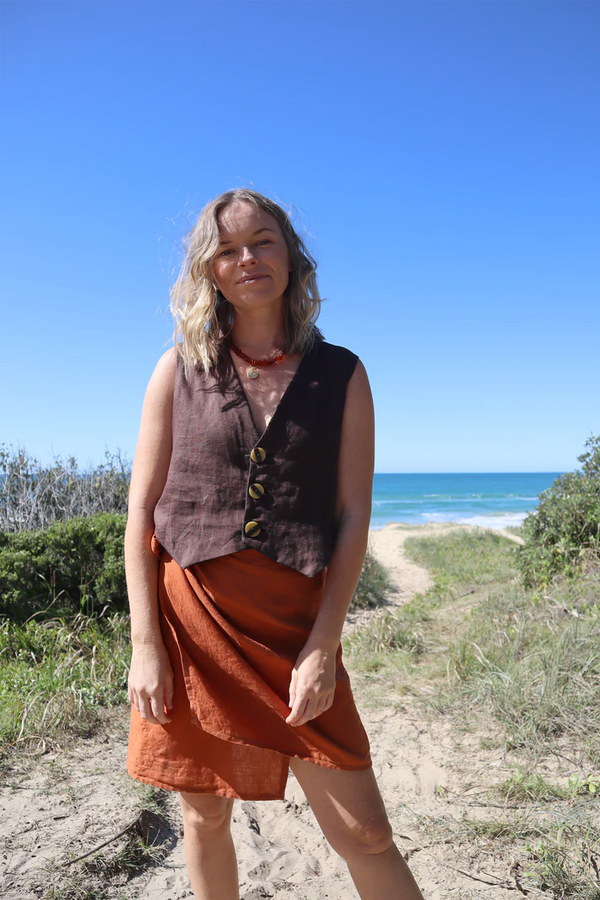 Pipit Vest Sewing Pattern - Reversible Oversized Vest in Two Lengths. Image of A woman wearing pipit vest made of brown colour linen fabric in the beach side