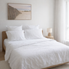 Neatly made bed with white bedding in a bright bedroom.