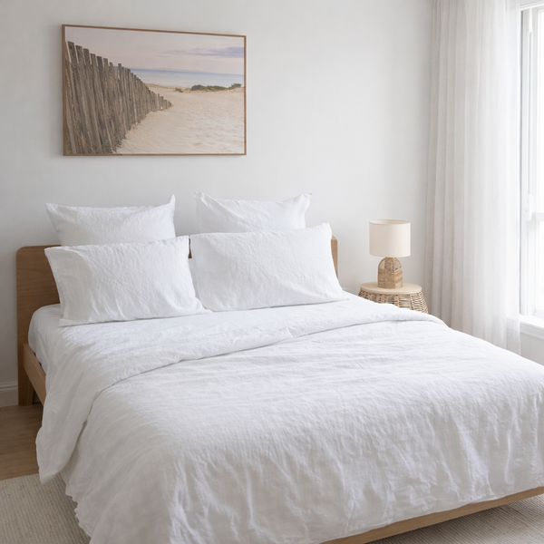 Neatly made bed with white bedding in a bright bedroom.