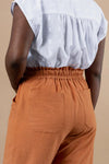 Person wearing a white blouse and brown pants made using Sepia Pants and Shorts sewing pattern on a beige background
